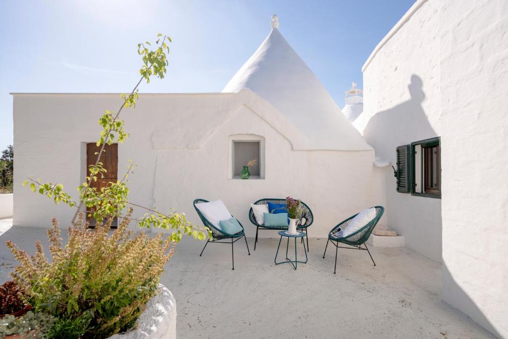 Un patio con sillas y una mesa y un edificio. en Trulli in Contrada - Monopoli, en Monopoli