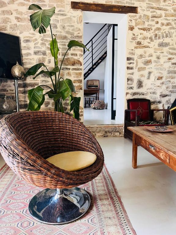 un fauteuil en rotin dans un salon avec une table dans l'établissement L'Ostal des Embruscalles, à Claret