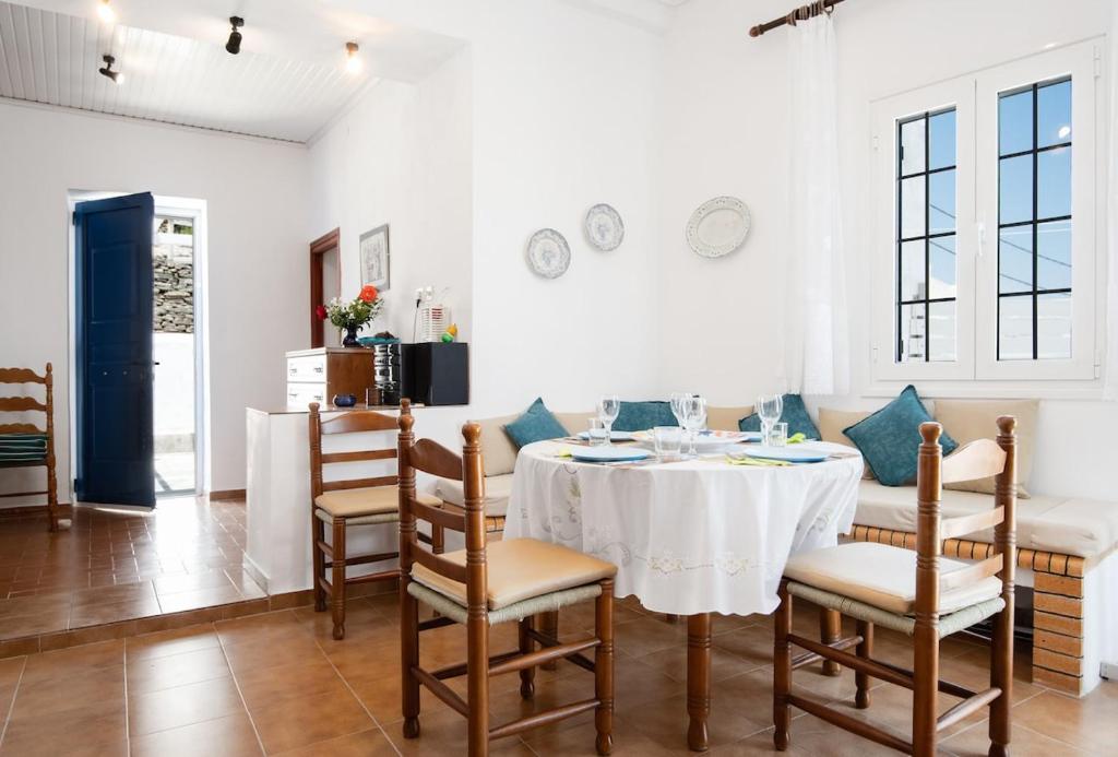 a dining room with a white table and chairs at VORINI'S HOUSE, Exampela,Sifnos in Katavatí