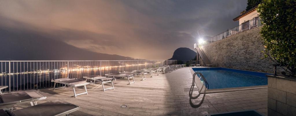un balcone con piscina e sedie a sdraio di notte di La Quiete 30 Lake view apartment by Gardadomusmea a Tremosine Sul Garda