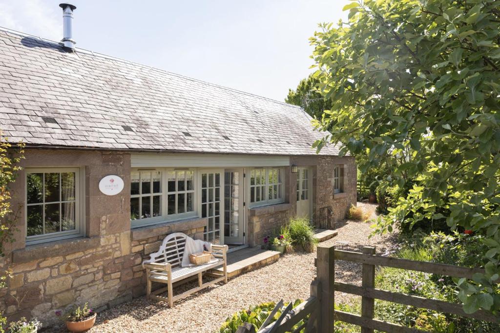 an old stone cottage with a bench in front of it at The Heritage Cottage in Swinton