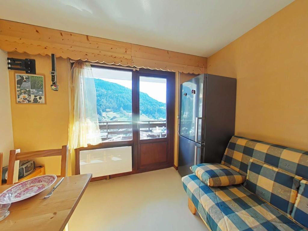 un salon avec un canapé et une grande fenêtre dans l'établissement Studio ensoleillé avec balcon Sud, parking, navette, 4 couchages - Le Grand-Bornand - FR-1-241-98, au Grand-Bornand