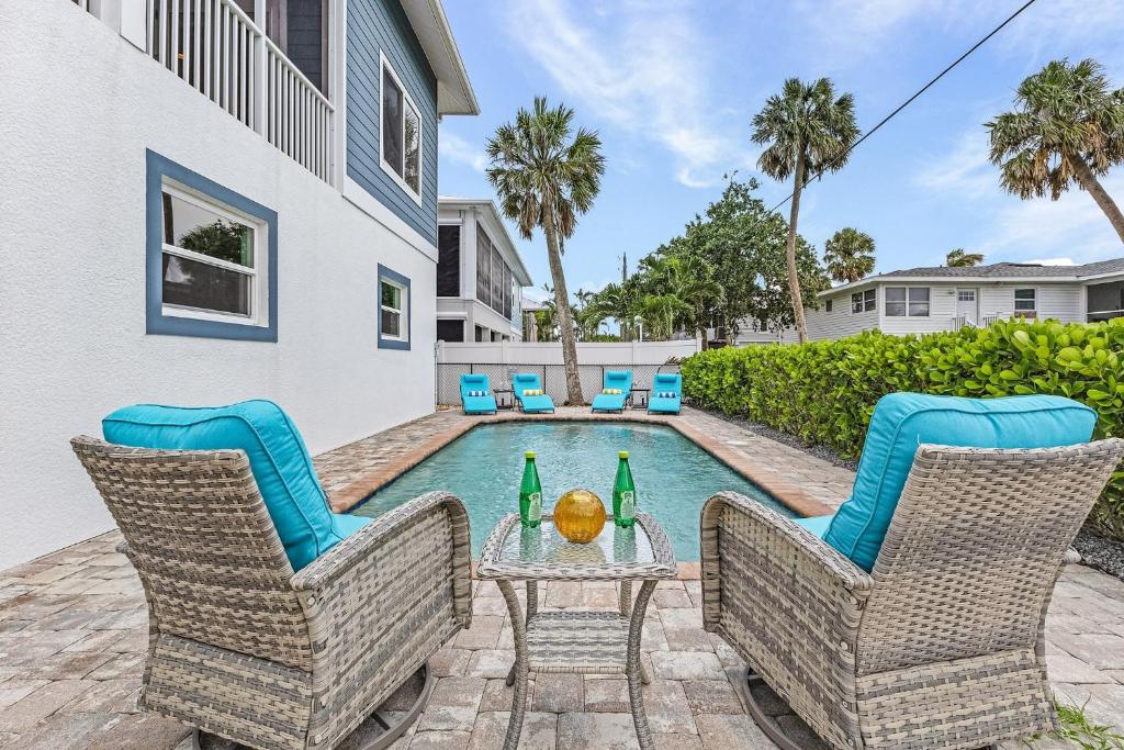 Una villa con piscina y dos sillas y una mesa con bebidas. en Close to Beach & Bay Retreat - Gulf Island Breeze - Roelens, en Fort Myers Beach