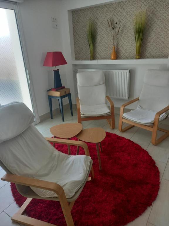 - un salon avec deux chaises et un tapis rouge dans l'établissement la plage, à Larmor-Plage