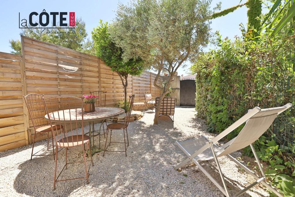 un patio avec une table et des chaises et une clôture dans l'établissement Le Petit Mas, à Carry-le-Rouet