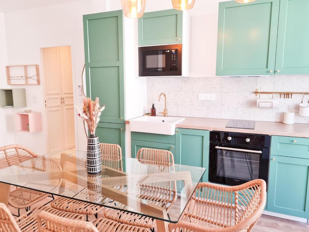 une cuisine avec des placards bleus et une table en verre avec des chaises dans l'établissement Appartement Prestige, Climatisation, Balcon, Nice, à Nice