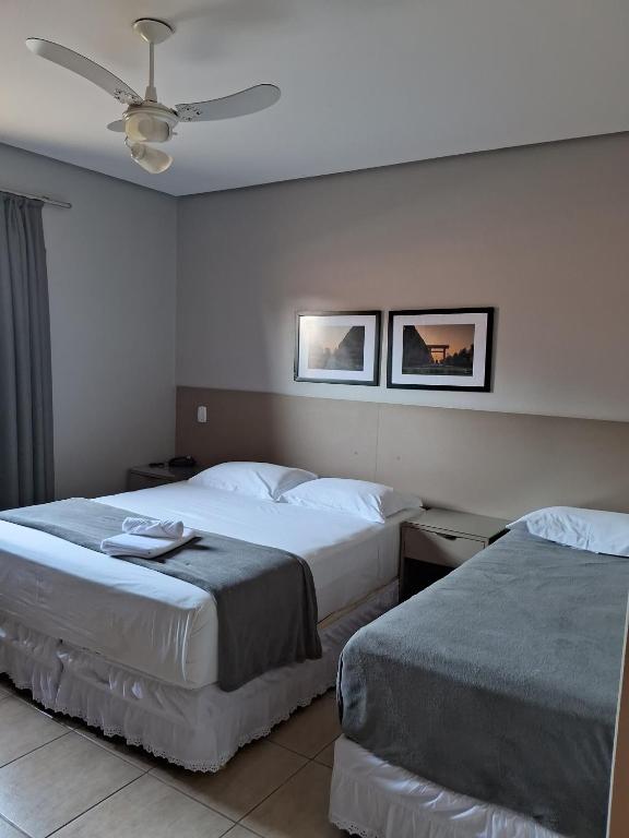 a hotel room with two beds and a ceiling fan at Pousada Villa da Mata in São Miguel Arcanjo