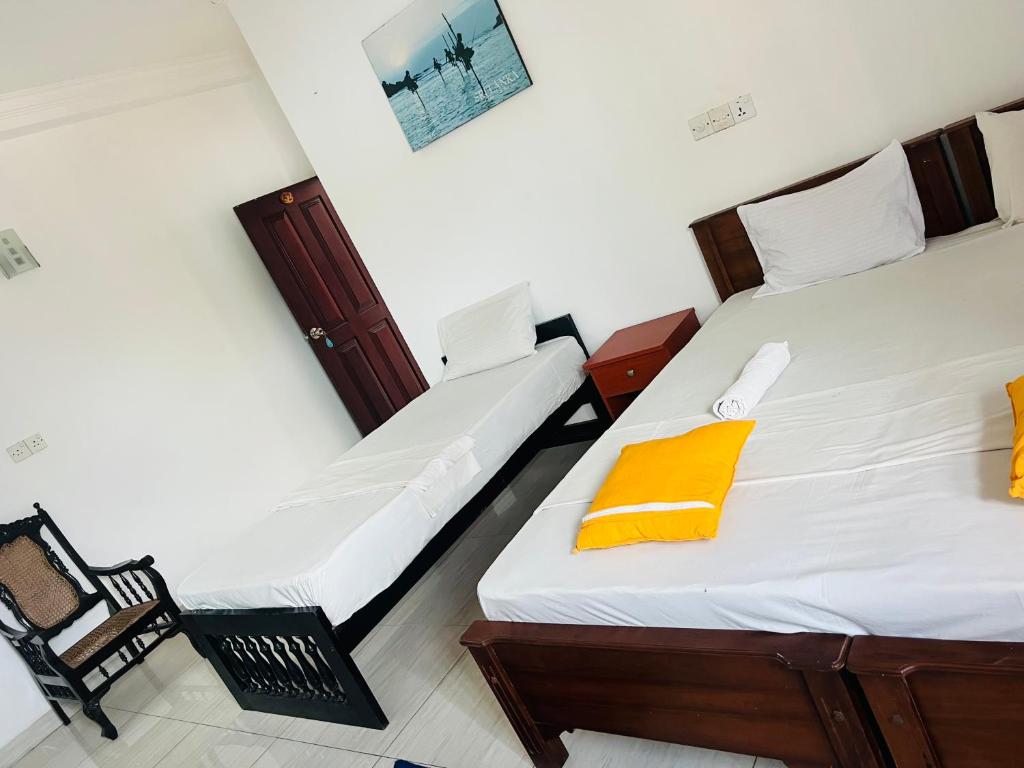 two twin beds in a room with a yellow napkin at Honey beach backpackers in Negombo