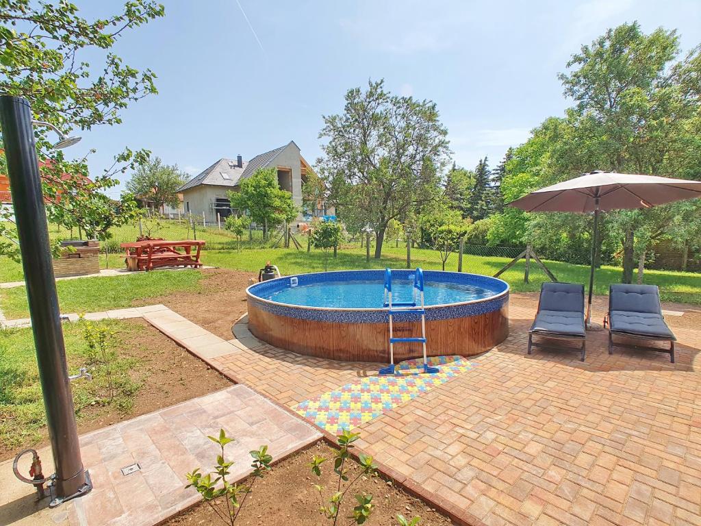 a swimming pool with two chairs and an umbrella at Holiday house Woody with private pool - Biró Tours nr 88 in Vonyarcvashegy
