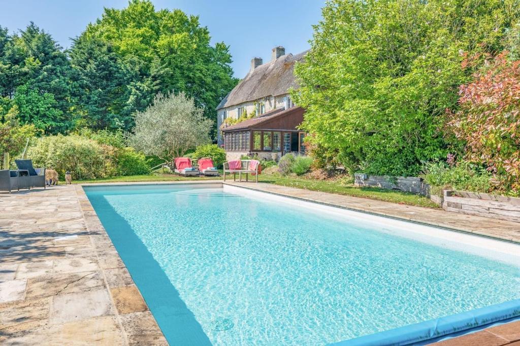 une piscine devant une maison dans l'établissement Greenhill Cottage Sea Views with Thatched Charm, à Beer