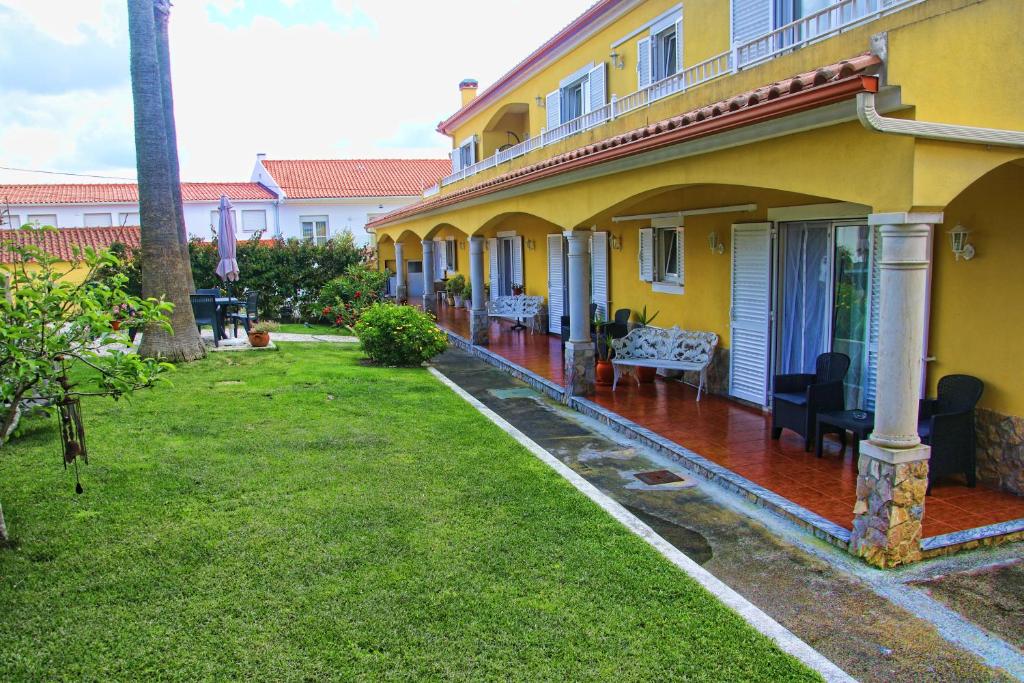 a yellow house with a green yard next to it at Casa das Palmas in Óbidos