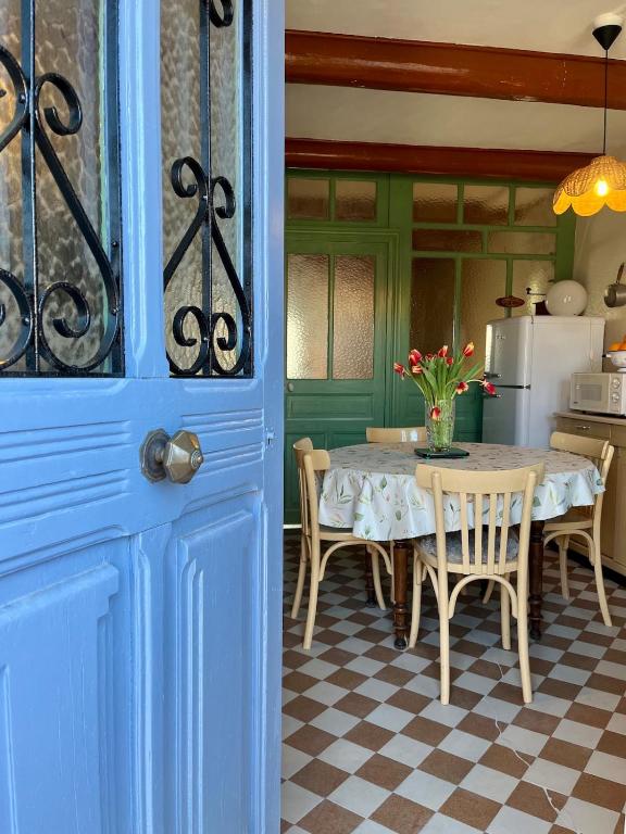 une cuisine avec une table et des chaises ainsi qu'une porte bleue dans l'établissement La Stuga, Gîte cocooning au cœur des volcans, à Ludesse