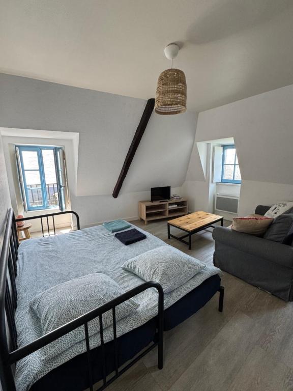 une chambre avec un lit et un canapé dans l'établissement Le CulSalé joli studio au cœur des remparts avec vue imprenable sur les toits, à Guérande