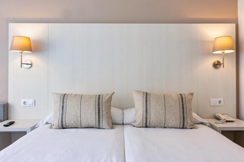 a bedroom with a white bed with two pillows at Minura Sur Menorca in Punta Prima