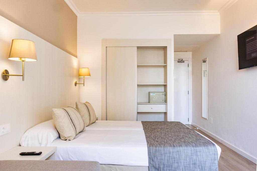 a hotel room with a white bed and a shelf at Minura Sur Menorca in Punta Prima