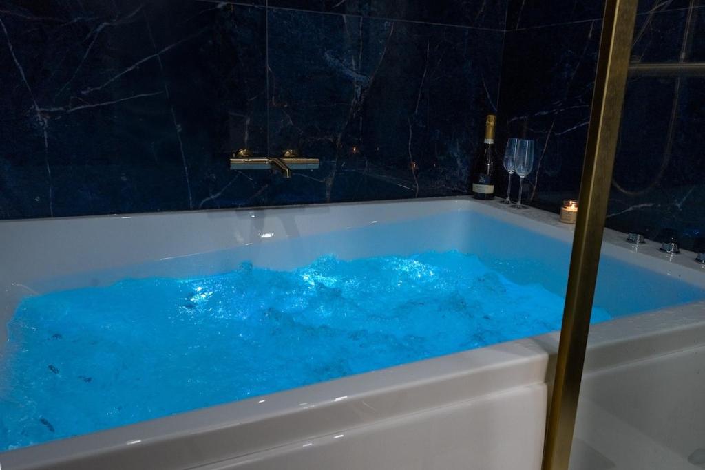a tub filled with blue water in a bathroom at Le Passion Room - Love Room - Jacuzzi in Beauvais