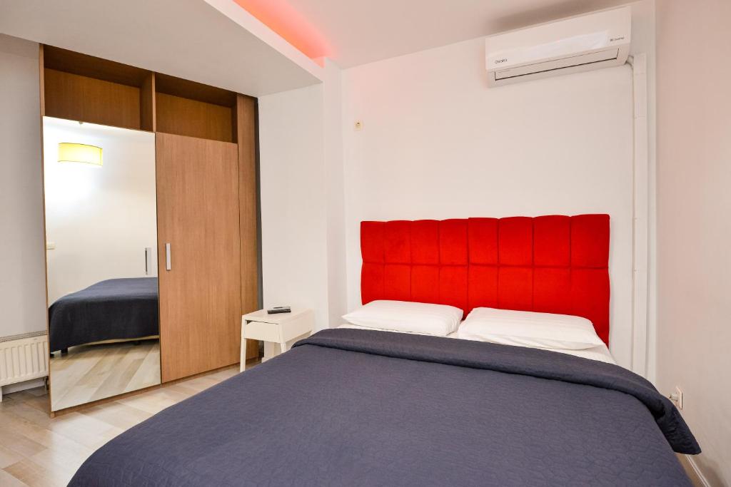 a bedroom with a bed with a red headboard at Royal Accommodation in Bucharest
