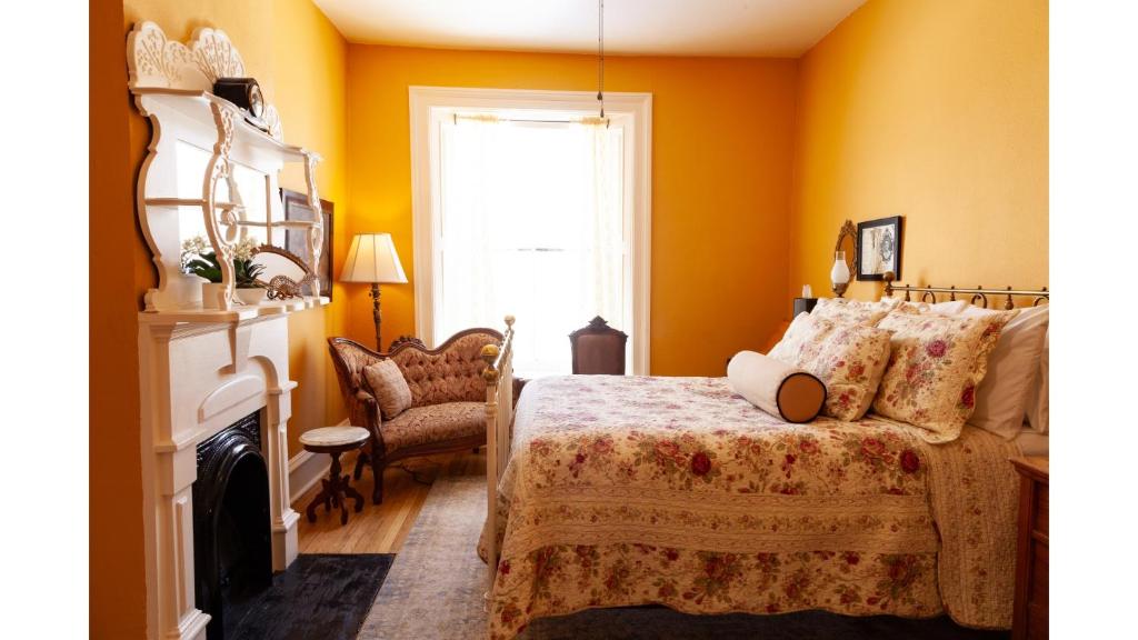 a bedroom with yellow walls and a bed and a window at Mary Lambert - Historic Hotel in Cimarron