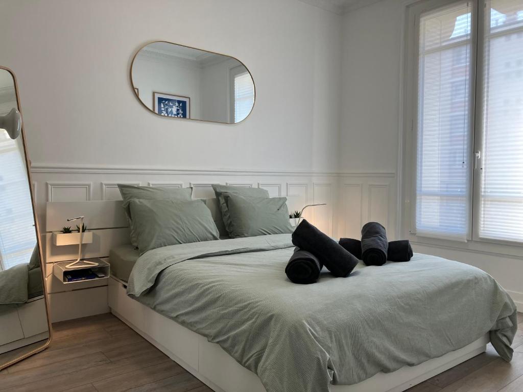 - une chambre blanche avec un grand lit et un miroir dans l'établissement Charmant appartement décoré proche du parc des expositions, à Paris