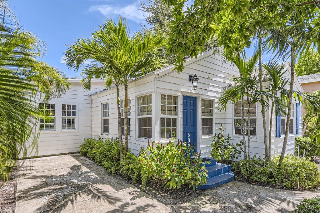 a white house with palm trees in front of it at Palm Beach Oasis - Indulge in Garden Tranquility with Alfresco Dining in West Palm Beach