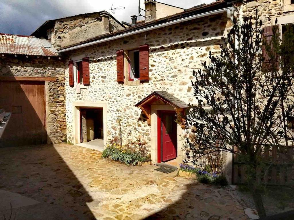 un bâtiment en pierre avec une porte rouge et un arbre dans l'établissement Calme d'Amont, à Formiguères
