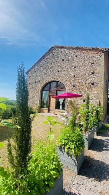 un bâtiment en briques avec un parapluie rose dans un jardin dans l'établissement La Bastide de Marie & Pascal, à Larroque