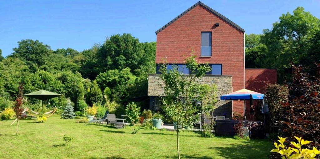 a brick house with a yard with tables and umbrellas at Housedurbuy 2 in Durbuy