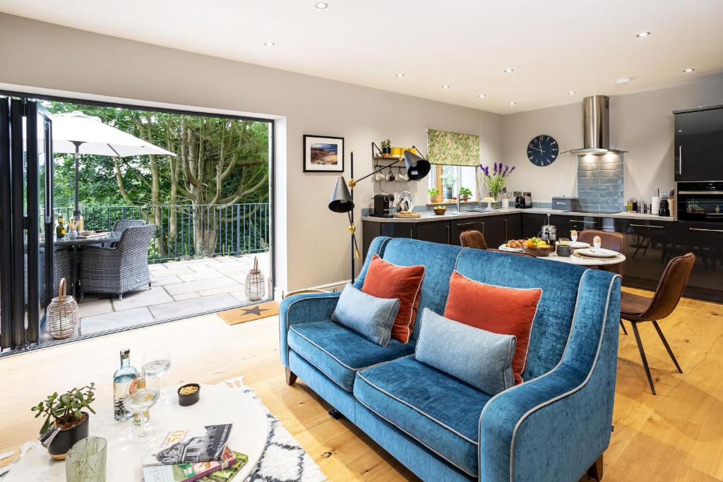 a living room with a blue couch and a kitchen at Hen Harrier Lodge in Lancaster