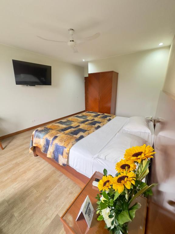 a bedroom with a bed and a table with flowers at Hotel Esencia Suites in Lima