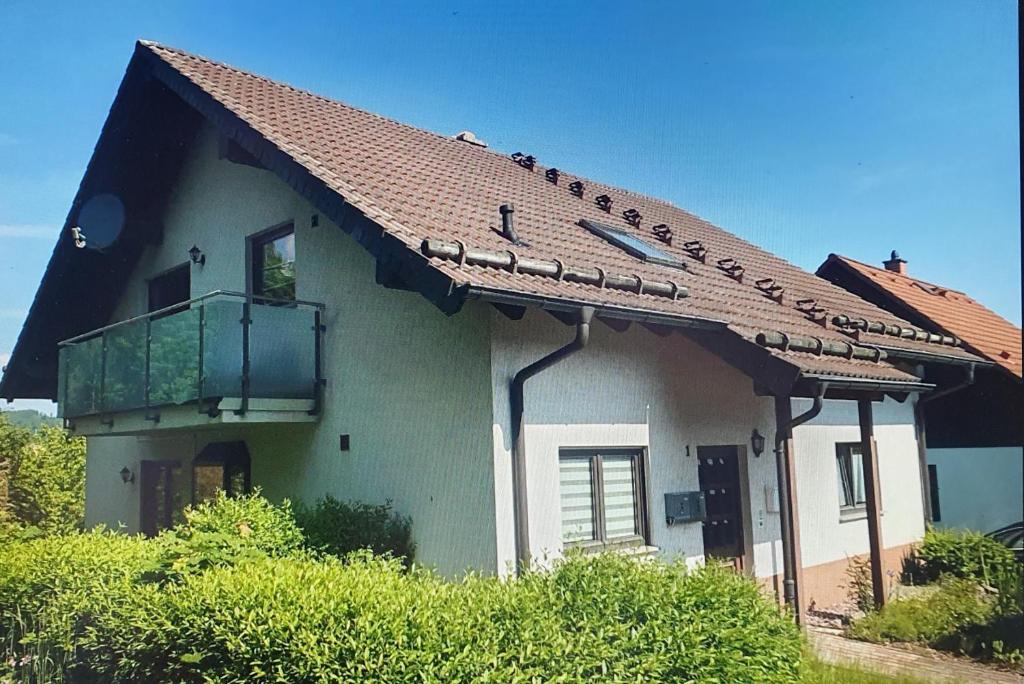 a house with a red roof and a balcony at Ferienwohnung Hüttenholzstraße in Ilmenau