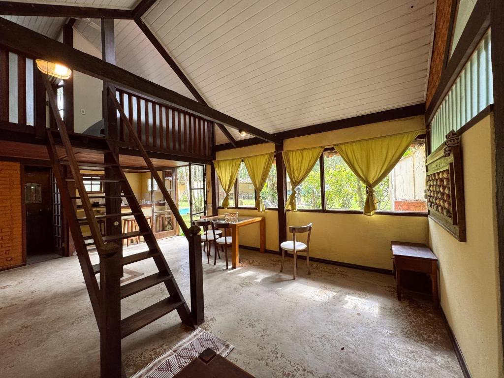 Una habitación con una escalera y una mesa y ventanas. en Casa Pindorama - Chalé Opy, en Paraty