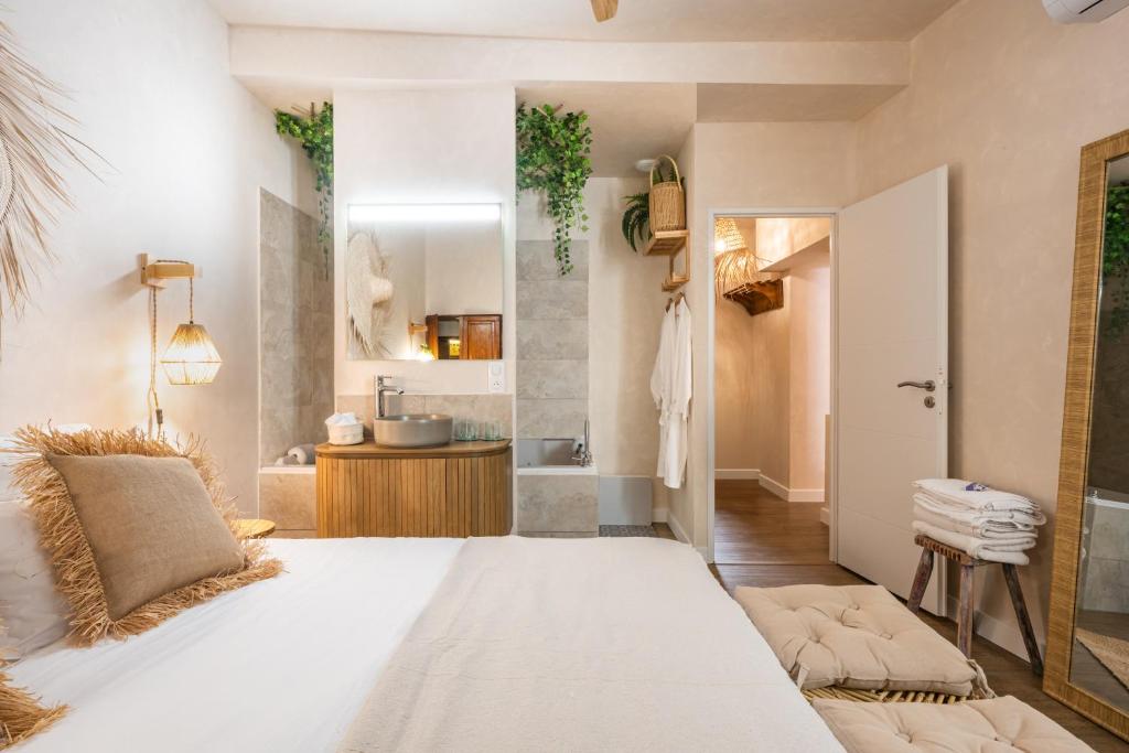 La salle de bains est pourvue d'un grand lit blanc et d'un lavabo. dans l'établissement Le Jardin Secret - Suite Bali avec Balnéo, à Carpentras