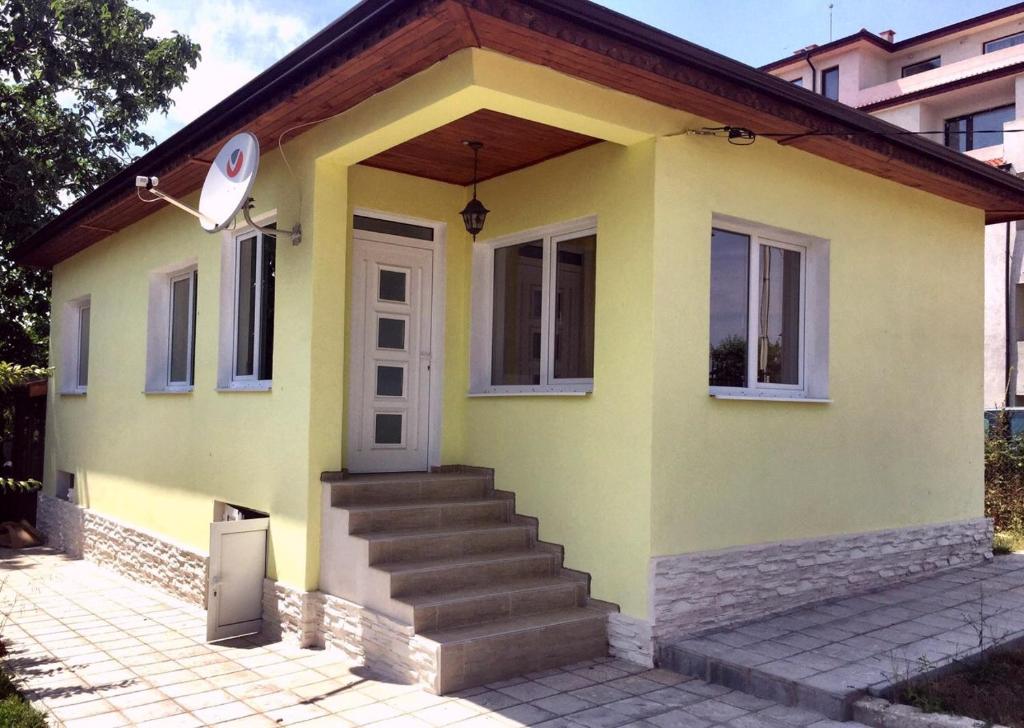 a small yellow house with stairs in front of it at Вила НАДЕЖДА in Byala