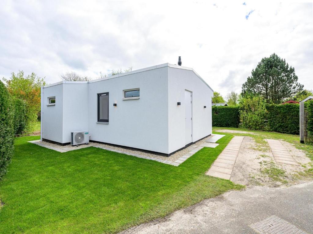 a white house with a green yard at Eureka 36 bungalow for 4-guests with garden in Sint Maartensvlotbrug