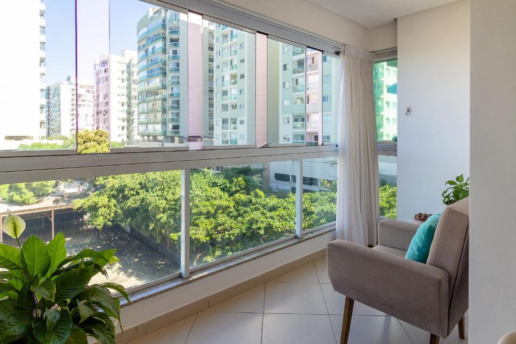a living room with a large window and a chair at 2Q Casal • Suíte c/ AC • Vista • 2º Andar • NOMDS in Itaparica