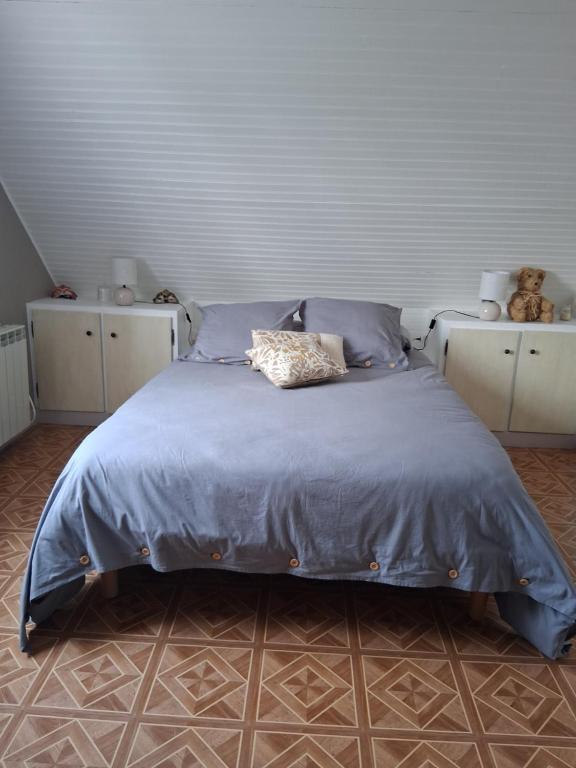 a bed with a blue comforter in a bedroom at La chambre aux papillons in Huismes