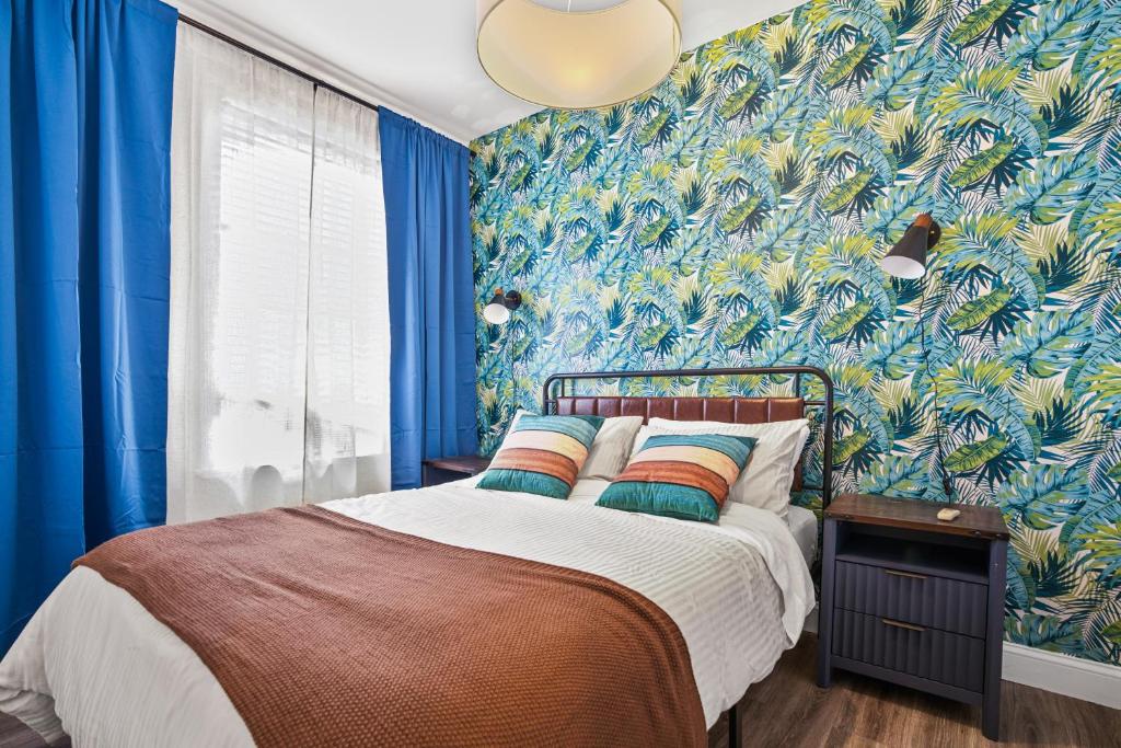 a bedroom with a bed with blue walls and a tropical wallpaper at 2BD Urban Ease in Lower East Side in New York