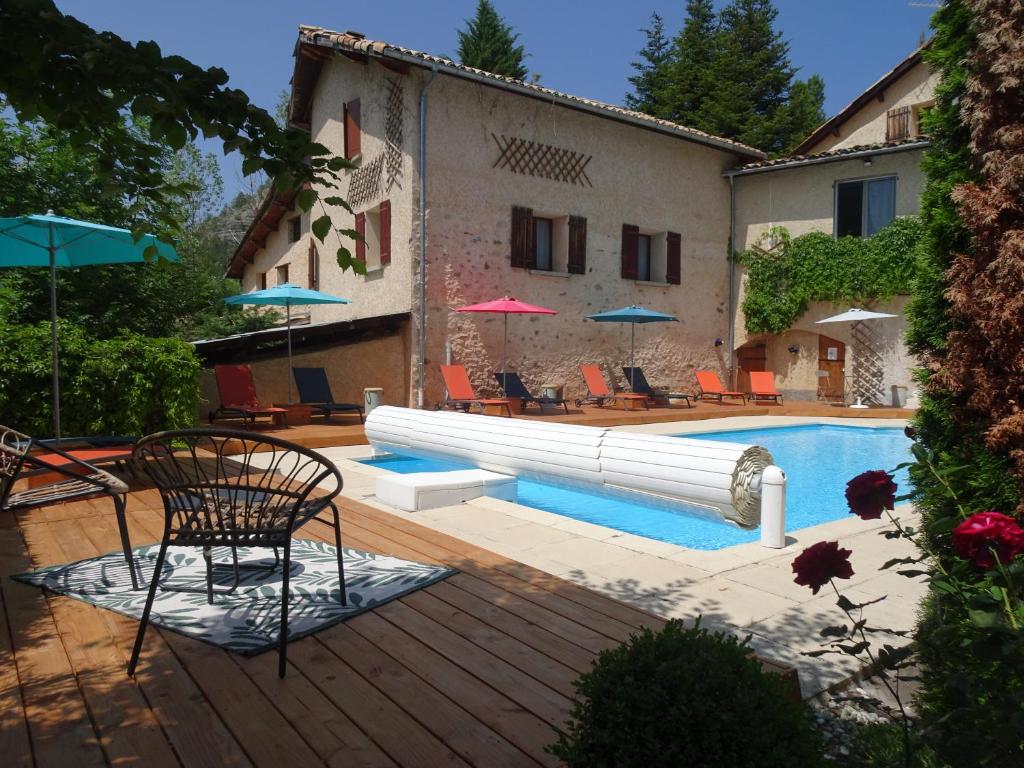 a pool with chairs and umbrellas next to a building at La Méridienne - Gite Ceusette in Venterol