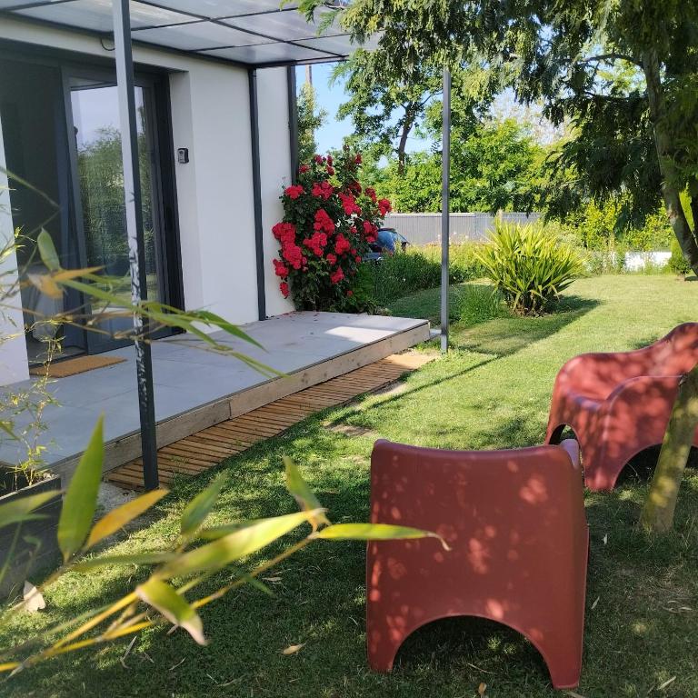 une chaise rouge assise dans l'herbe devant une maison dans l'établissement Le Logis de la Voie Verte, à Saint-Amadou