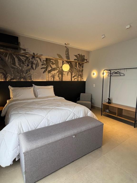 a bedroom with a large white bed and a chair at ID Vida Urbana Studio Floresta in Goiânia