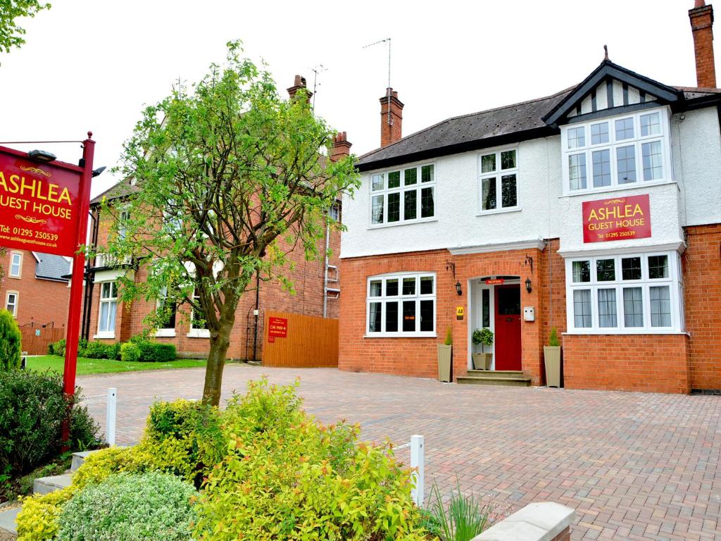 a brick building with a red door on a street at Ashlea Guest House in Banbury