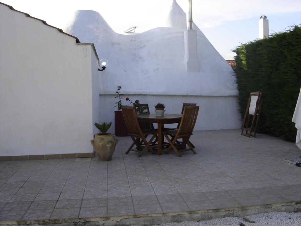 a patio with a table and chairs next to a white wall at Trulli Sarmenzanello in Noci