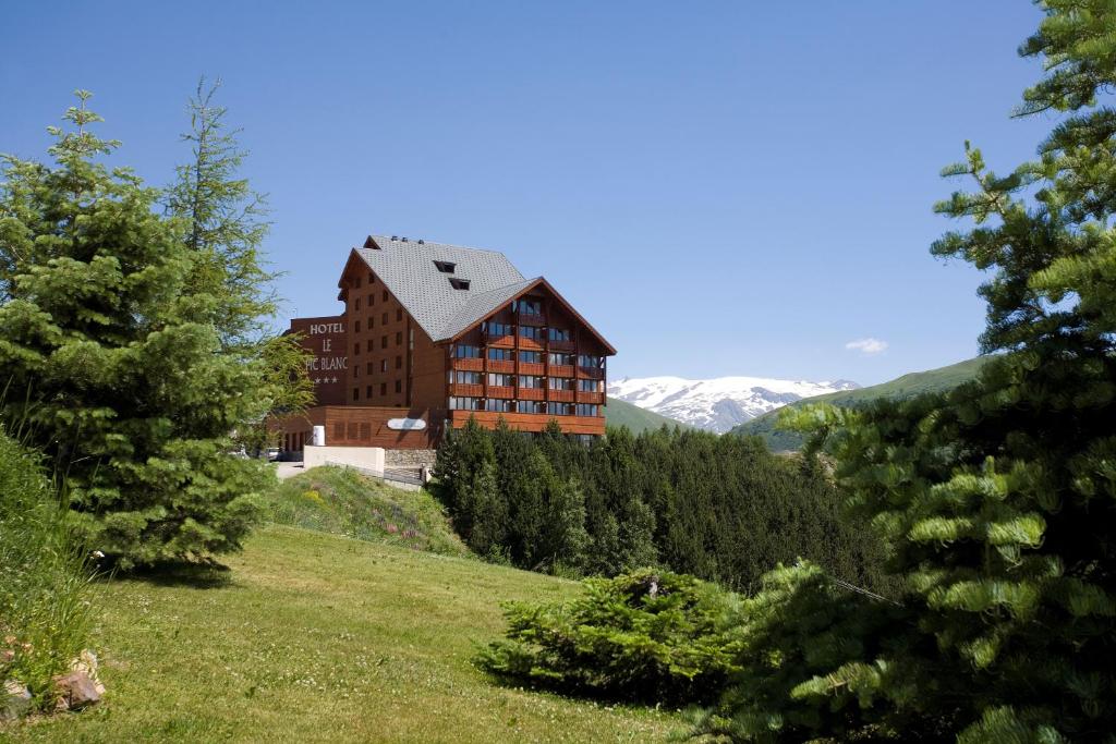une maison sur une colline avec des montagnes en arrière-plan dans l'établissement Le Pic Blanc, à L'Alpe-d'Huez