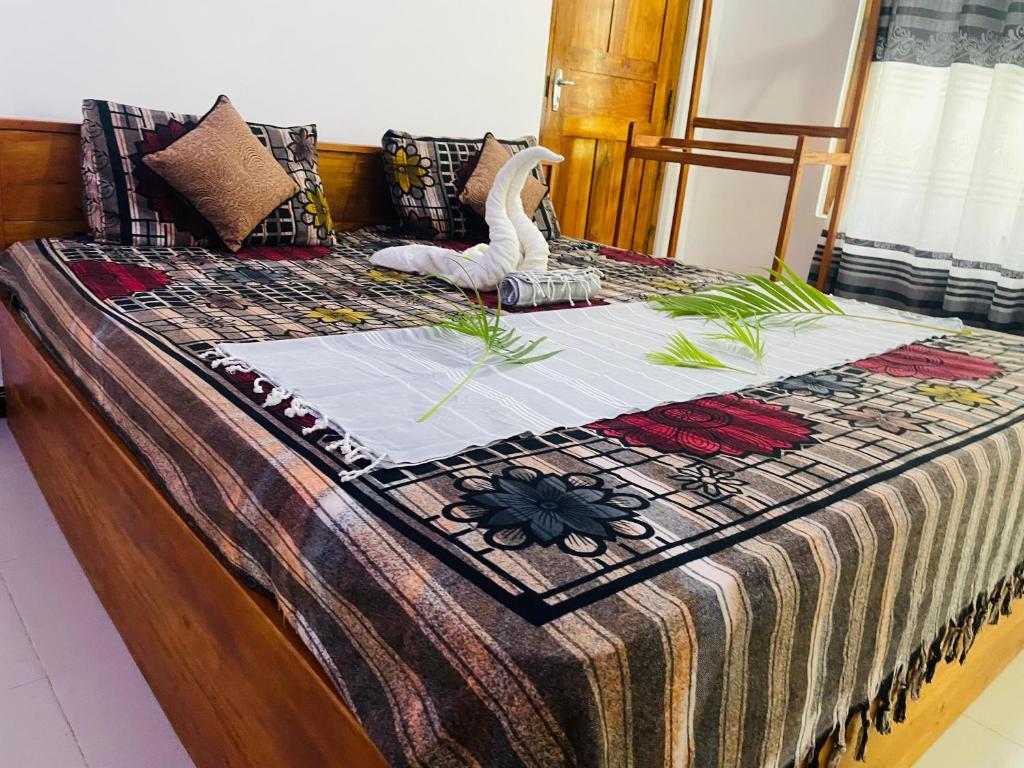 a bed with a quilt with a swan on it at Trinco Shalom Guest & Restaurant in Trincomalee