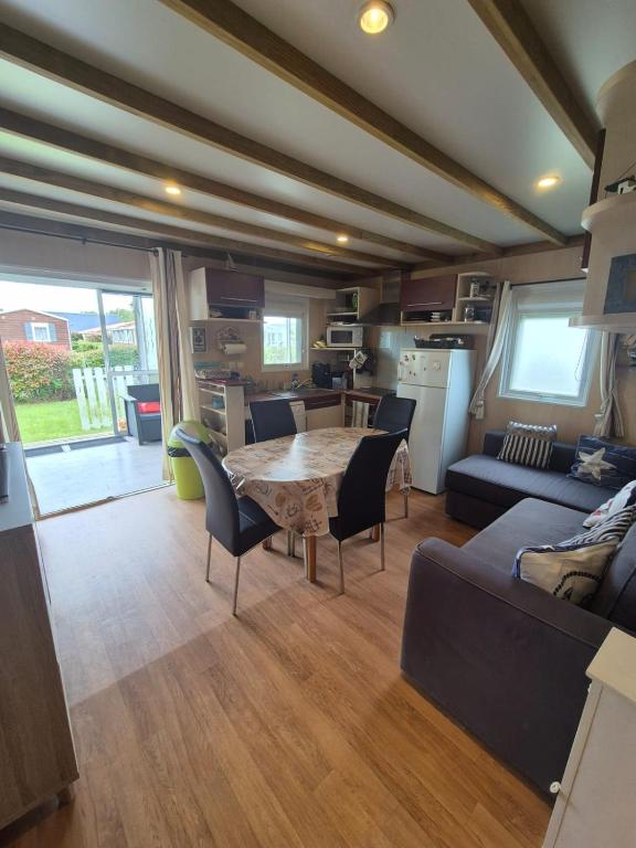 un salon avec une table et un canapé dans l'établissement Chalet avec piscine proche de la plage, à Grandcamp-Maisy
