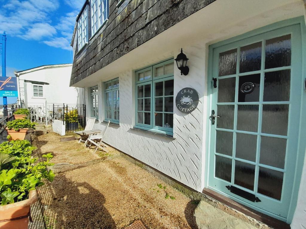 a white house with a blue door and windows at Crab Cottage in Ilfracombe