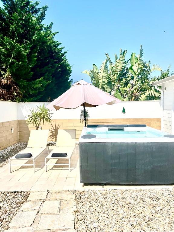a swimming pool with two chairs and an umbrella at Polignano Villa with Jacuzzi, Garden & Parking in Polignano a Mare