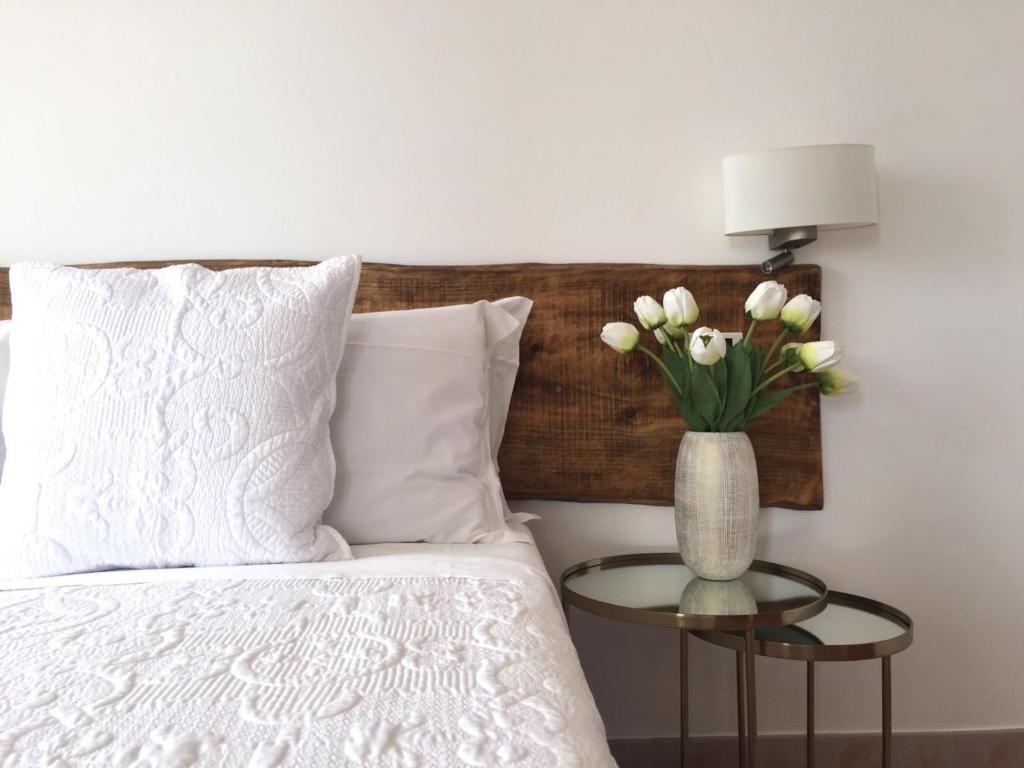 Una cama con un jarrón con flores blancas sobre una mesa en Villa Charme, en San Marzano sul Sarno