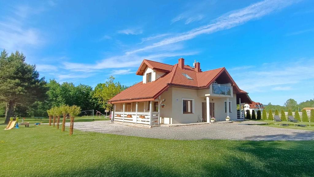a house with a red roof on a green field at Agroturystyka Serce Łysicy in Święta Katarzyna
