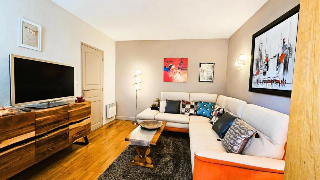 a living room with a white couch and a flat screen tv at Gîte de France Les saulieres 3 épis - Gîte de France 10 personnes MAE-1323 in Monceaux-sur-Dordogne
